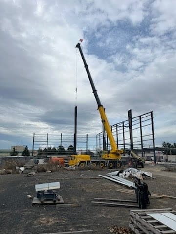 All-terrain crane setting structural steel columns on a commercial construction site