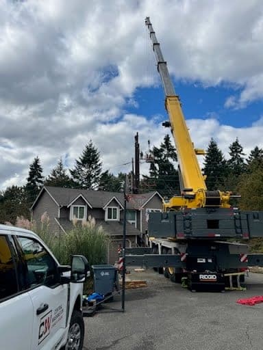 CW Crane & Rigging all-terrain crane and company service truck set up on a residential jobsite