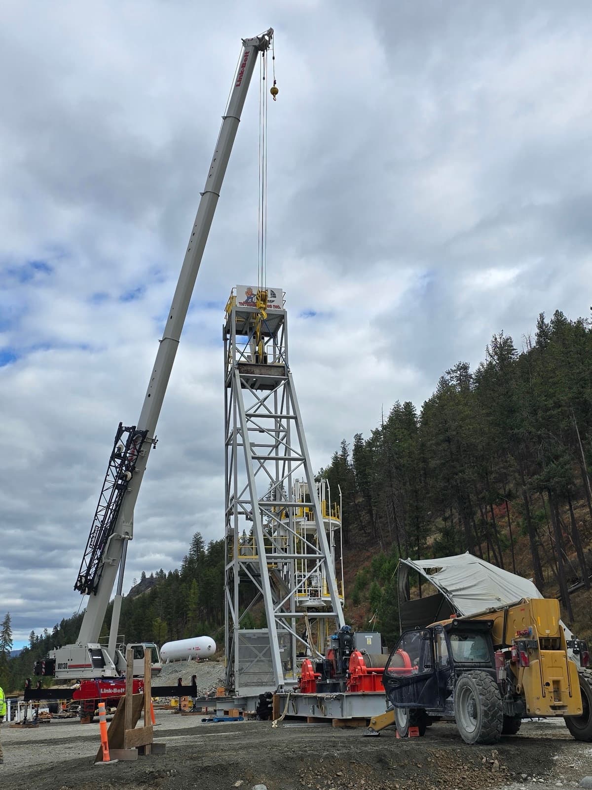 CW Crane & Rigging Link-Belt 130-ton rough-terrain crane boomed up beside a steel mine headframe it is helping erect